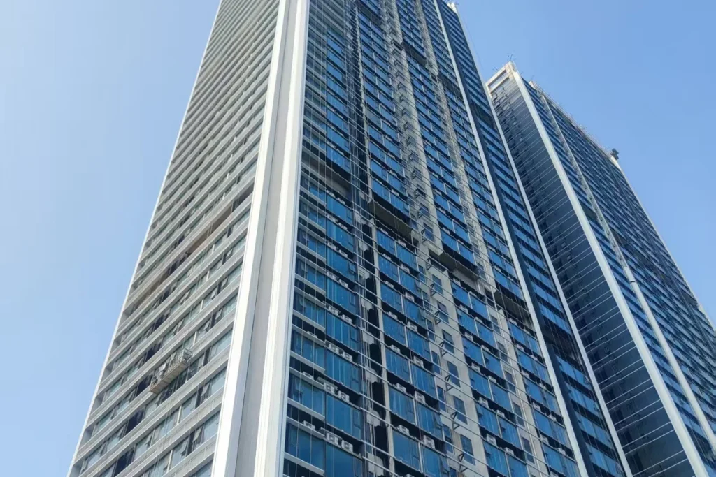 High-rise mixed-use tower in the Qiandeng Lake CBD of Foshan China, with continuous unitized curtain wall in blue-tinted low-E double glazing rising to a 40-storey parapet against a clear blue sky
