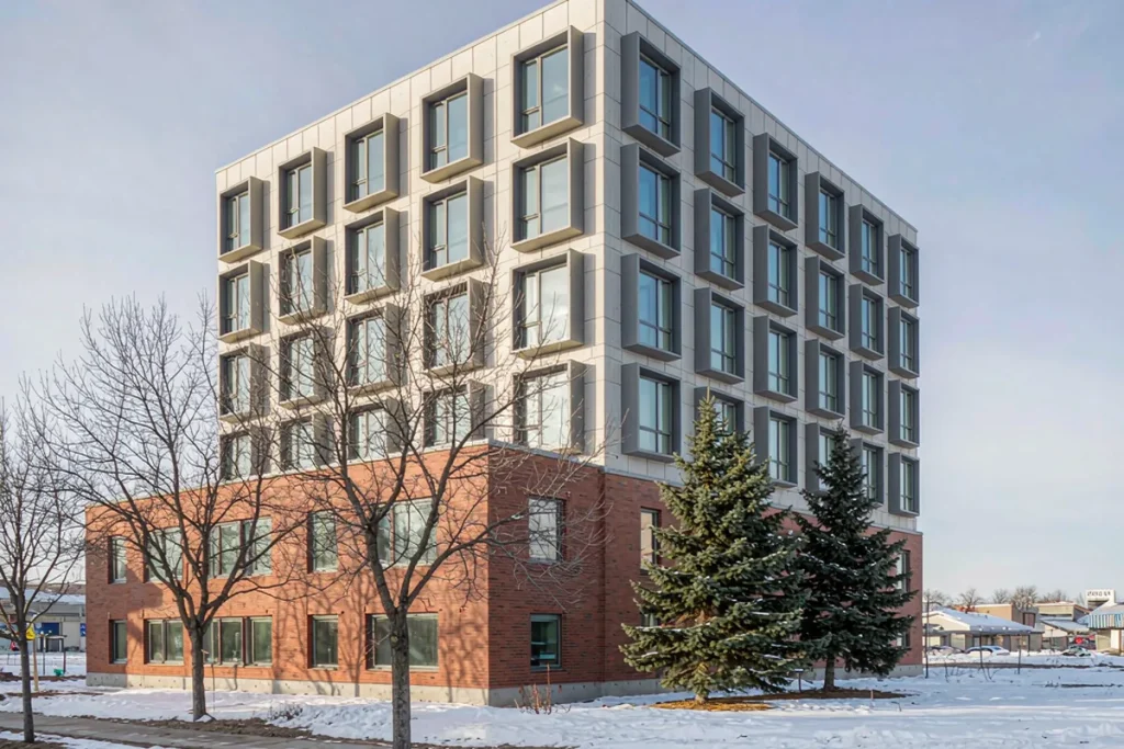Five-storey apartment building with panelized unitized facade cassettes and light snow on the ground