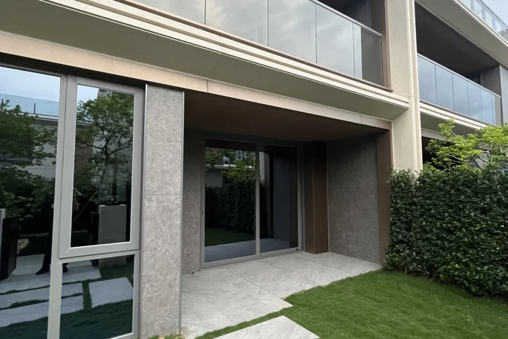 Premium private residence in Foshan by China Overseas Land, with large thermal-break aluminium sliding glass doors opening onto a stone-clad terrace and lawn