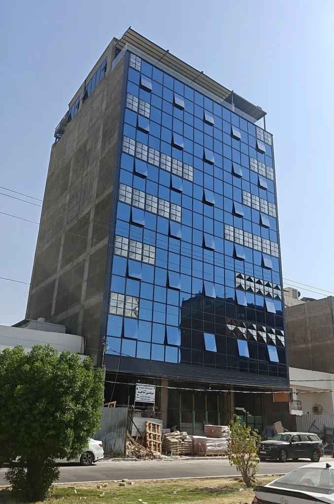 Completed blue-glazed stick curtain wall on the Baghdad commercial building, viewed from street level