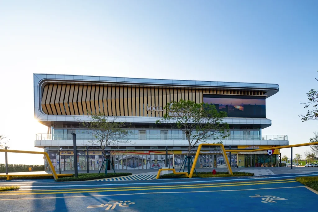 Completed Bangkok commercial showroom with a glazed ground floor, warm aluminium louvres and a deep cantilevered roof