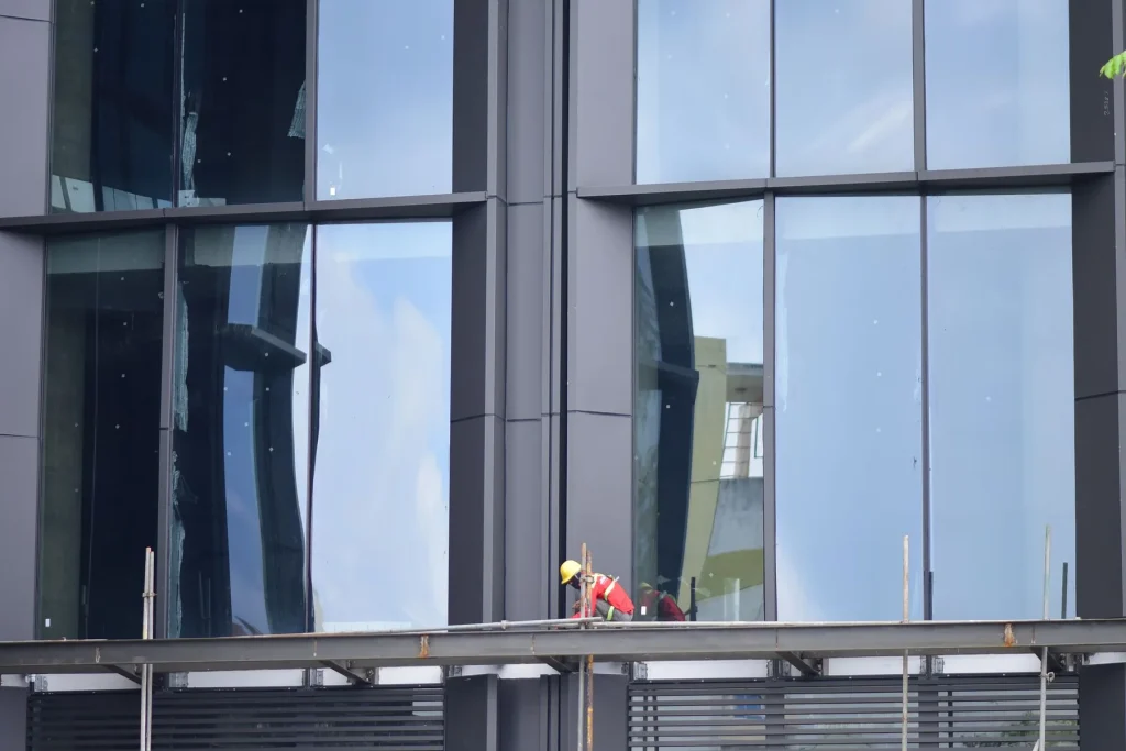 Facade installer working from scaffolding on a large glazed elevation